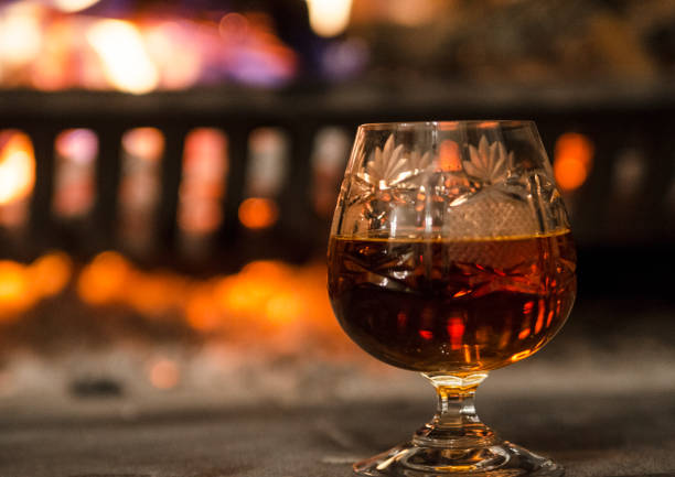 istock drink in single chrystal glass and blurred fireplace with burning fire background 1176535485