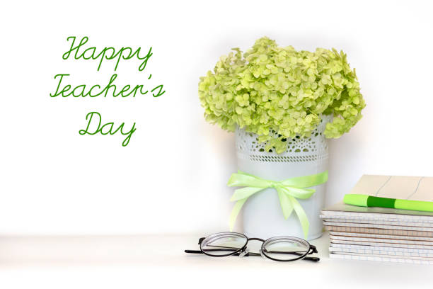 Happy Teachers Day Greeting Card Bouquet Of Light Green Hydrangea Branch In Flower Pot With Satin Ribbon Pile Of Notebooks Glasses And Pen On White Background International School Teacher Day Stock Photo - Happy Teachers Day Greeting Card Bouquet Of Light Green Hydrangea Branch In Flower Pot With Satin Ribbon Pile Of Notebooks Glasses And Pen On White Background International School Teacher Day Stock Photo -