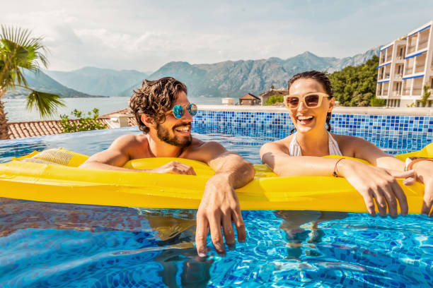 playful couple smiling in a pool - inflatable raft nautical vessel sea inflatable imagens e fotografias de stock