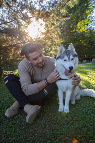 istock Happy young man sitting outside with his husky dog 1176540066