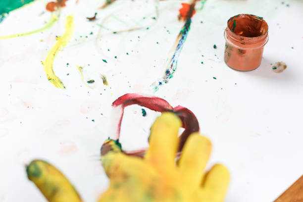istock yellow hands in paints on light table painted in different colors 1176544025
