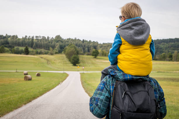 아들을 어깨에 짊어지고 아름다운 고원에서 길을 따라 하이킹하는 아버지 - assistance hiking child father 뉴스 사진 이미지