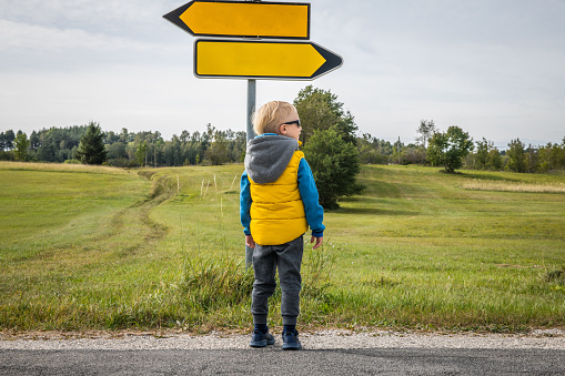 Left or Right, Little boy looking for direction in a beautiful green plateau