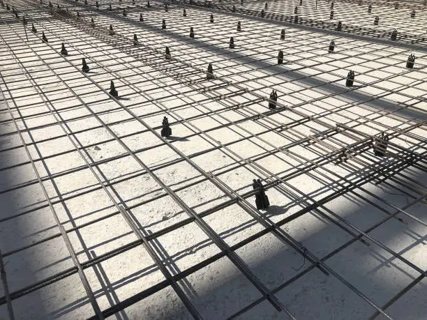 Photo of Metal reinforcement grid with plastic holders. Reinforced concrete preparation. Concrete basement construction
