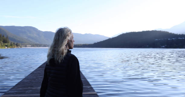 istock Woman walks along lakeside pier at sunrise 1176551162