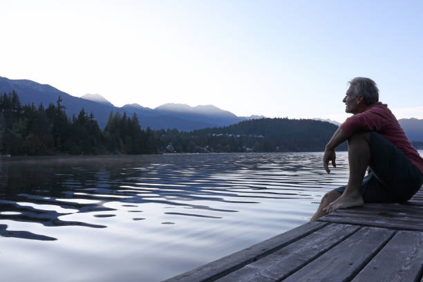 istock Man sits on lakeside pier at sunrise 1176554639