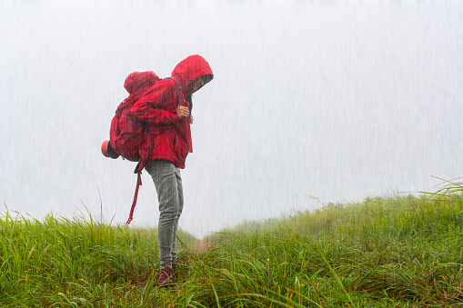 upset or disaster of woman traveller trekking on the meadow field at raining shower on the hill mountain
