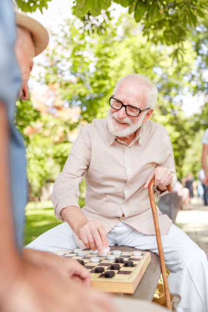 istock Smiling old man playing checkers with friend outdoors 1176557327