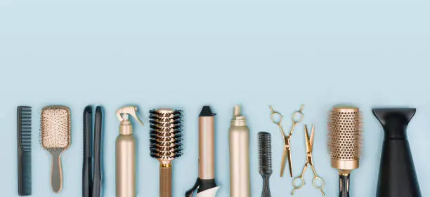 Photo of Hair stylist tools arranged in a line on blue background