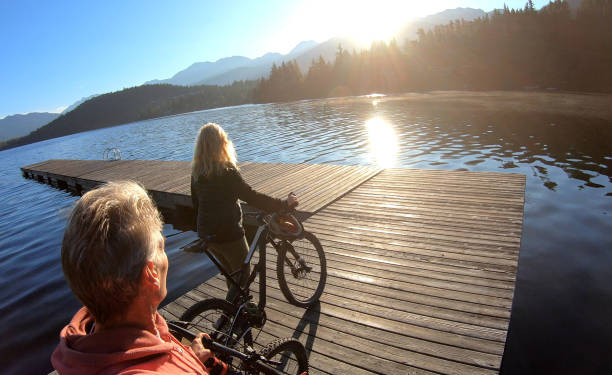 istock Couple walk bikes along lakeside pier at sunrise 1176559326