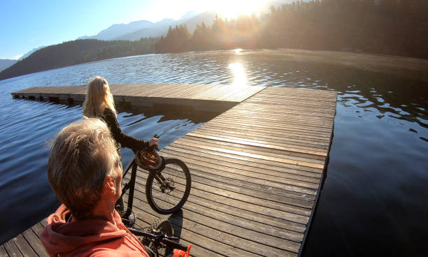 istock Couple walk bikes along lakeside pier at sunrise 1176559454