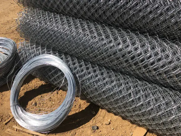 Metal mesh netting rolled into rolls and coils of steel wire. Rolled chain-link fence.