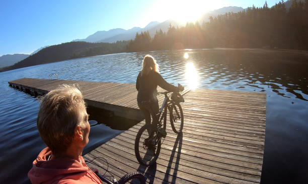 istock Couple walk bikes along lakeside pier at sunrise 1176560623