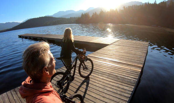 istock Couple walk bikes along lakeside pier at sunrise 1176560629