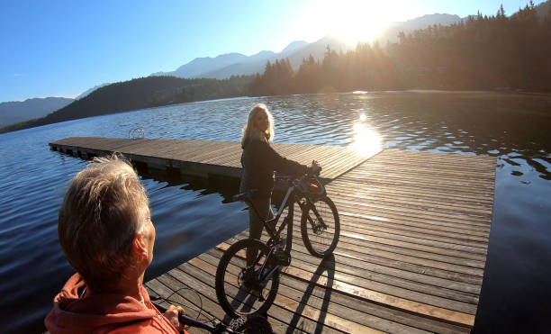 istock Couple walk bikes along lakeside pier at sunrise 1176560632