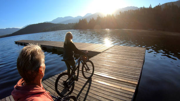 istock Couple walk bikes along lakeside pier at sunrise 1176560633