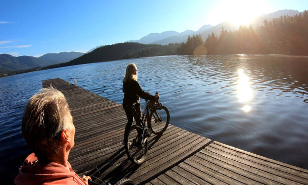 istock Couple walk bikes along lakeside pier at sunrise 1176560812