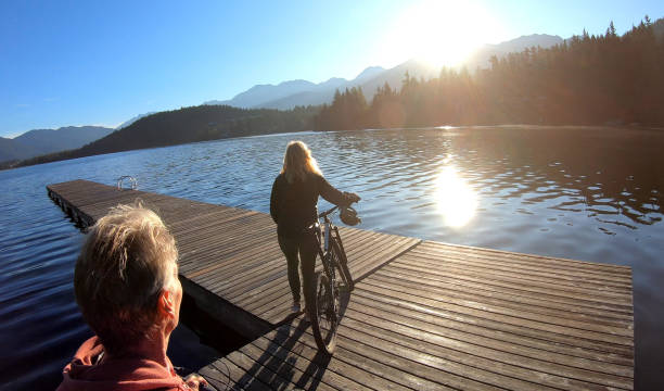 istock Couple walk bikes along lakeside pier at sunrise 1176560867