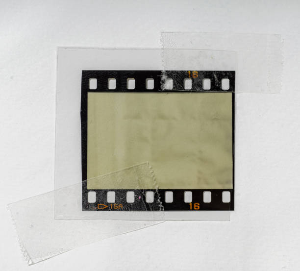 Real and original 35mm or 135 film material or photo frame on white background with cello tape on edges behind foil real 35mm film material with empty cell or frame in foil, macro photo, no scan 35mm movie camera stock pictures, royalty-free photos & images