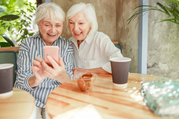 istock Mature women using smartphone and laughing at outdoor cafe 1176560892