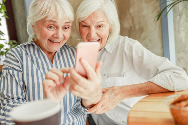 istock Cheerful senior women using smartphone at outdoor cafe 1176560925