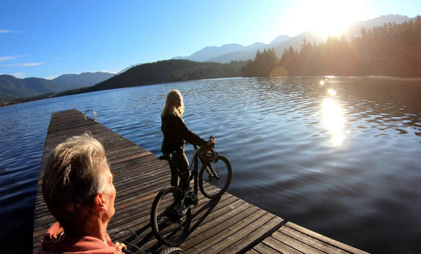 istock Couple walk bikes along lakeside pier at sunrise 1176561077