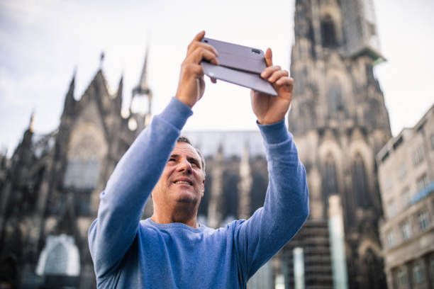 One man, mature gentleman using smart phone for taking pictures on the street in Cologne, Germany.