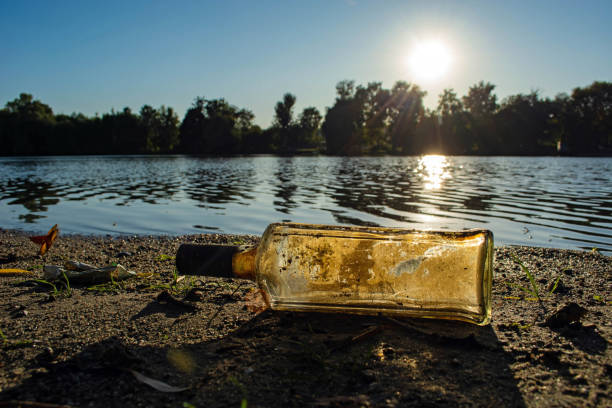 istock old glass bottle by the river. water pollution concept 1176562453