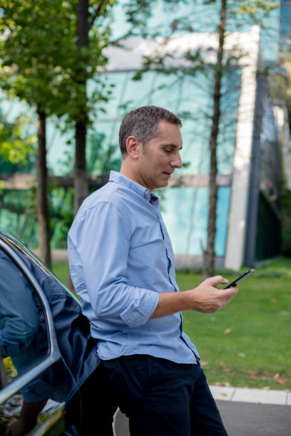 istock Casually dressed businessman using his smartphone on the parking 1176562701