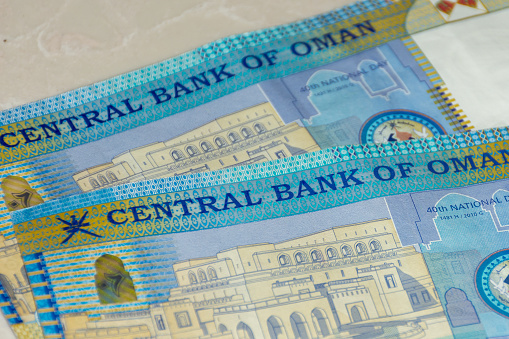 A close up of the Central Bank of Oman 20 Riyal bills of cash, the currency of the Oman notes spread out on a semi white background.. Money exchange.