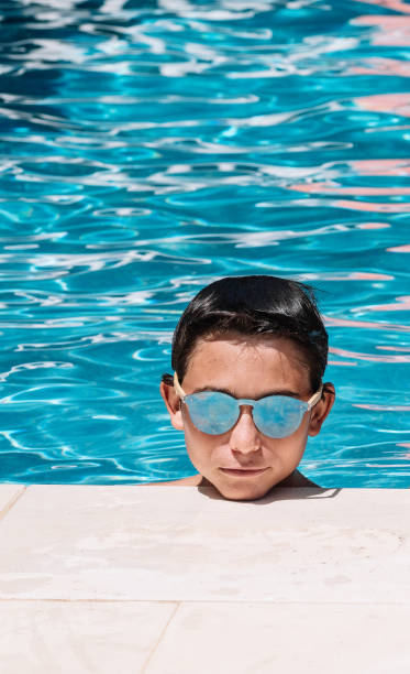 istock Pre-teens pose with sunglasses by the edge of the pool 1176567456