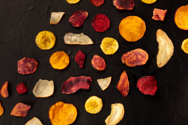 istock Dry fruit and vegetable chips, shot from the top on a black background with a place for text. Healthy vegan snack, an organic food flat lay pattern with copy space 1176567458
