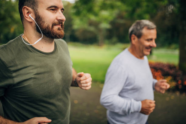 istock Senior man and son jogging in park 1176569479