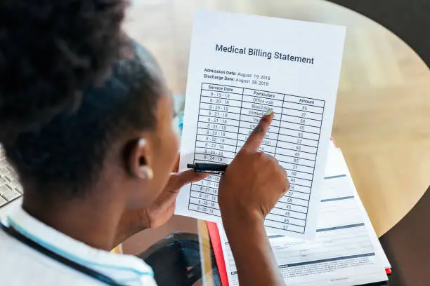 Photo of Healthcare costs and fees concept.Hand of smart doctor calculating medical costs in modern hospital. Doctor completing a Medical Claim Form by Stethoscope