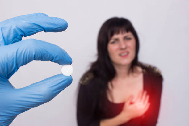 el médico sostiene la píldora en la mano del sistema cardiovascular, la niña paciente se para en el fondo y se aferra al corazón, problemas cardíacos, - human hand help pain heart attack fotografías e imágenes de stock