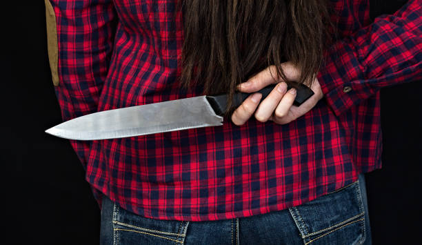 девушка, держащая нож за спиной, черный фон, крупным планом - retribution стоковые фото и изображения
