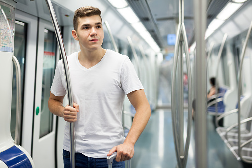 Young male passenger in casual clothing with baggage in subway