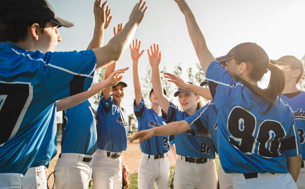 gruppe von baseballspielern, die zusammen auf dem spielplatz mit handfeier stehen - baseballmannschaft stock-fotos und bilder