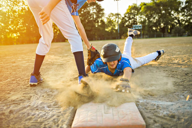 o grupo de dois jogadores de basebol joga junto no campo de jogos. sobre eles slide sobre o gol - baseball cap cap men baseball - fotografias e filmes do acervo