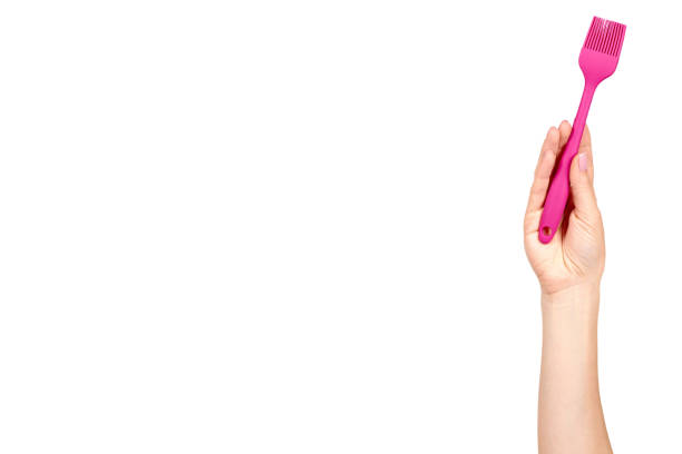 Hand with pink culinary brush, kitchen utensil. Isolated on white background. Copy space template.