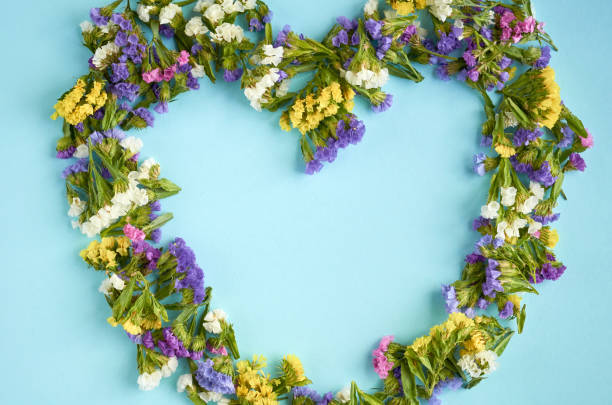 istock Colored flowers on blue background composition, heart shape. Flat lay 1176578519