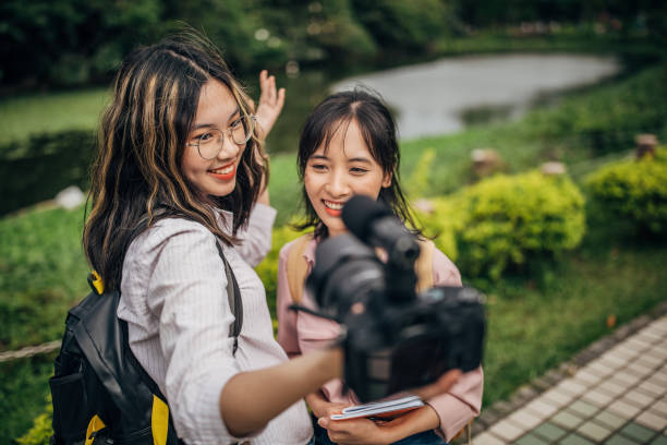 istock Two young ladies students vlogging in park 1176578639