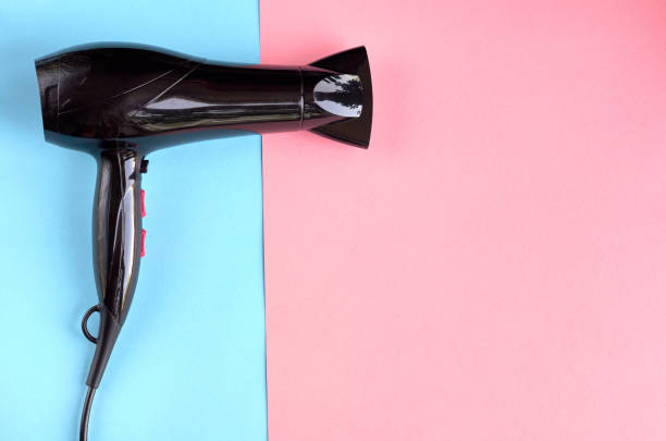 istock Black hair dryer on blue and pink background composition. 1176578982