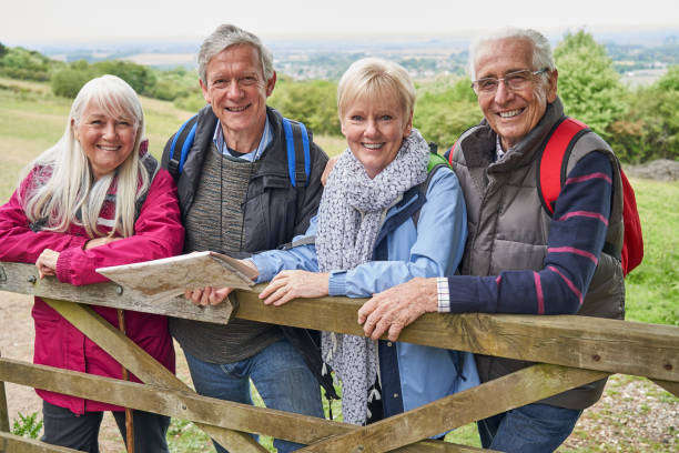ritratto di gruppo di amici anziani che escursioni in campagna in piedi vicino al cancello - bag senior adult outdoors friendship foto e immagini stock