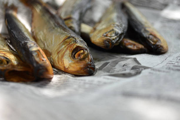 Delicious golden smoked fish on newspaper. Closeup.
