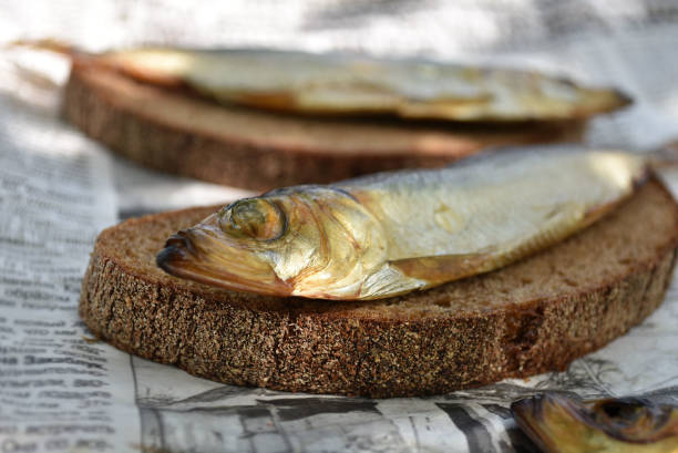 istock Golden smoked fish on newspaper. Fish on bread. 1176584798