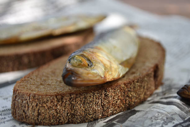 istock Golden smoked fish on newspaper. Fish on bread. 1176584857