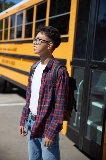 istock Male student is standing near school bus 1176587725