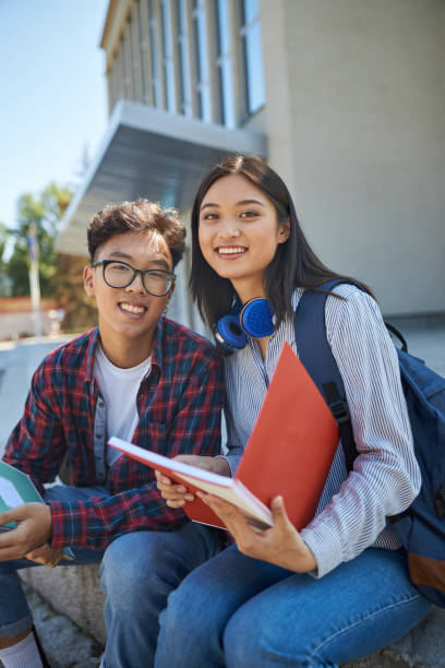 istock Two smiling Asian students are sitting outdoors 1176588055