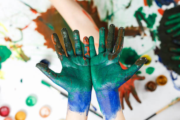 istock green hands in paints on background of light table painted in different colors 1176589899